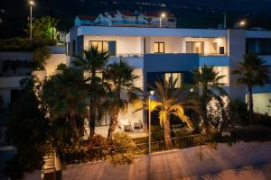 a large white building with palm trees in front of it at Paoma Luxury Beach Suite with jacuzzi in Podstrana