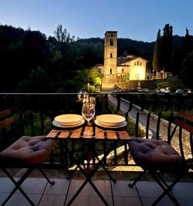a wooden table with plates and wine glasses on a balcony at Nonnas little house on the river in Castelnuovo di Garfagnana