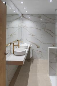 a bathroom with two sinks and a marble wall at Hotel & Restaurante El Casino in Villafranca del Bierzo
