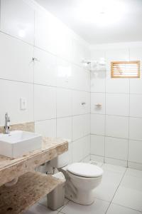 a white bathroom with a toilet and a sink at Mandacaru Flat in São Miguel do Gostoso