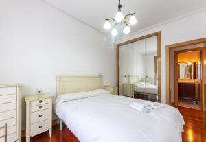 a bedroom with a white bed and a mirror at Bilbao BEC with parking by Aston Rentals in Barakaldo