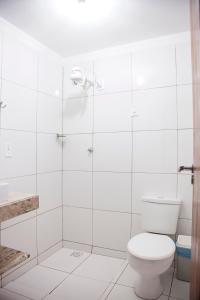 ein weißes Badezimmer mit Toilette und Dusche in der Unterkunft Mandacaru Flat in São Miguel do Gostoso