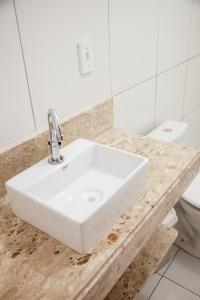 a bathroom with a white sink and a toilet at Mandacaru Flat in São Miguel do Gostoso