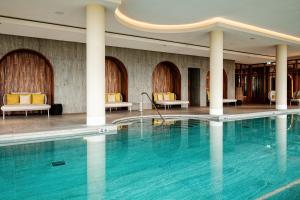 a swimming pool in a hotel lobby with chairs and tables at Van der Valk Hotel Eindhoven-Best in Best