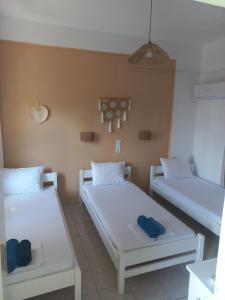 two beds in a room with white beds at Stafylos Rooms in Stafylos