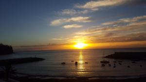 a sunset over the ocean with boats in the water at Apartamentos Tapahuga in Playa de Santiago