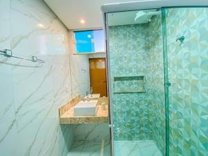 a bathroom with a sink and a glass shower at Ap 2 quartos espaçoso in Natal +29 photos