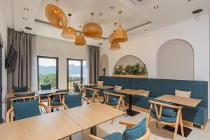 a restaurant with wooden tables and blue chairs at Hotel AQUILO in Petrovac na Moru