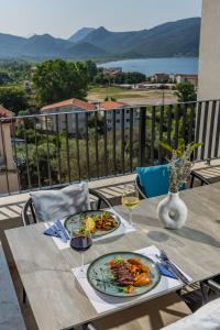 a table with two plates of food and glasses of wine at Hotel AQUILO in Petrovac na Moru