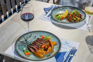 two plates of food on a table with a glass of wine at Hotel AQUILO in Petrovac na Moru