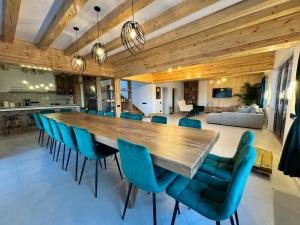a dining room with a large wooden table and blue chairs at Cabana Brad Apuseni Villa in Cotorăşti