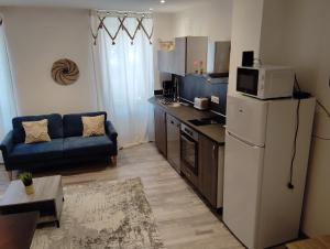 a kitchen with a refrigerator and a couch in a room at Maison chez Marthe in Le Muy