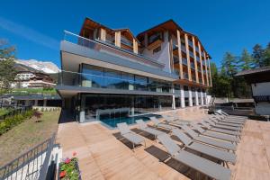 a house with a swimming pool and lounge chairs at Ciampedie Luxury Alpine Spa Hotel in Vigo di Fassa