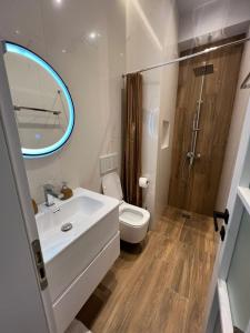 Un baño con lavabo, inodoro y espejo. en Cloud Cane Apartment, en Tirana