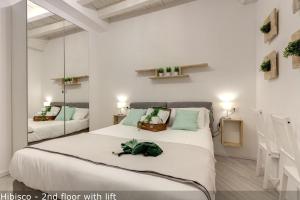 a white bedroom with a large bed and a mirror at Mamo Florence - Vertical Garden Apartments in Florence