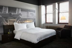 a bedroom with a large white bed and a chair at Hôtel Le Germain Québec in Quebec City