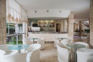 a restaurant with white chairs and tables and a bar at Hotel Plaza in Milano Marittima