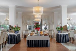 a dining room with tables and chairs and a chandelier at Hotel Plaza in Milano Marittima +46 photos