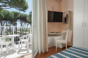 a room with a bed and a desk and a balcony at Hotel Plaza in Milano Marittima