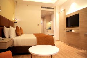 a bedroom with a bed and a couch and a tv at Best Western Vrindavan in Vrindāvan