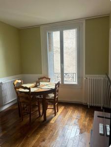 a dining room with a table and chairs and a window at Nid douillet proche de Paris in Sarcelles