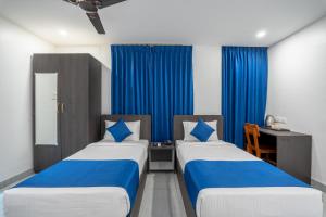 two beds in a room with blue curtains at Hotel G Skyla Srirampura Malleshwaram in Bengaluru