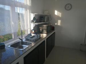 a kitchen with a sink and a clock on the wall at Ô Bercail du Sud chez Jeannette in Rodrigues Island +23 photos