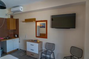 una camera con due sedie e una TV a schermo piatto a parete di Prego Living Apartments a Vathí