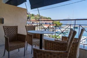 a table and chairs on a balcony with a view of the water at Prego Living Apartments in Vathí