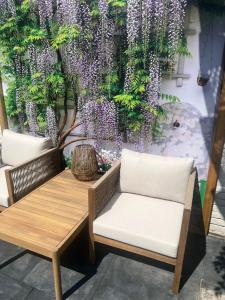 a bench and a table with purple flowers on a wall at Hartje Bergen in Bergen