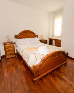 a bedroom with a wooden bed with two night stands and a window at Apartamentos Camino Inglés in Ordes +32 photos