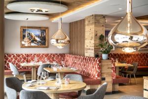 a restaurant with tables and chairs and chandeliers at Ciampedie Luxury Alpine Spa Hotel in Vigo di Fassa