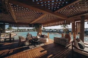 a wooden patio with a table and chairs next to a pool at Le Sidi - A TLT Signature Hotel in El Alamein