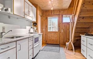 a kitchen with white cabinets and a wooden wall at 4 Bedroom Pet Friendly Home In Thyholm in Thyholm