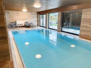 a large swimming pool with blue water in a house at Haus Wenger Mountain View & Swimming Pool in Kaprun