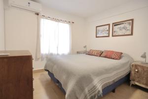 a white bedroom with a bed and a window at M. BERNARD in Concordia
