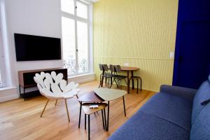 a living room with a couch and chairs and a tv at La Rêverie - Deluxe Apartment - SPA - Place du Forum in Reims