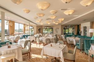 a restaurant with white tables and chairs and windows at Hotel Quinta do Lago in Quinta do Lago
