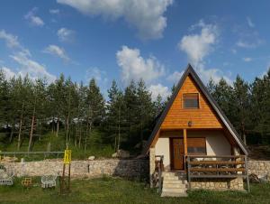 a small cabin with a fence and a stone wall at Srce Zminice in Žabljak