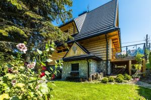 a log house with a porch and flowers at Willa Gocówka & SPA in Bukowina Tatrzańska
