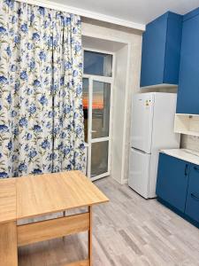 a kitchen with blue cabinets and a white refrigerator at Dastur in Taldykolʼ