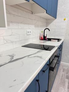 a white kitchen with a sink and blue cabinets at Dastur in Taldykolʼ