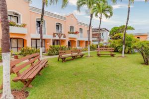 a row of park benches in a yard with palm trees at GB103 Village a 150m da Praia em Guarajuba, 2/4 in Guarajuba