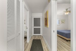 a hallway with a bed and a bedroom with white walls at Pelican Watch 604 condo in Fort Myers Beach