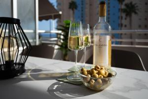 une bouteille de vin et un bol d'olives sur une table dans l'établissement Aquamarina I Calpe, apartement by the beach, à Calp