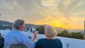 an older couple sitting on a balcony watching the sunset at Mosaics Guest House in Jaipur