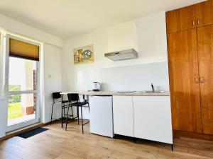 a kitchen with white cabinets and a counter top at Na Poczatku - Apartamenty in Darłowo