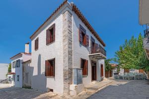 a white building with wooden windows on a street at Telegraphus Boutique Home in Skiathos
