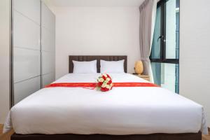 a white bed with a red ribbon and a flower on it at The Halo 1 Naiyang Beach in Nai Yang Beach