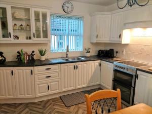 a kitchen with white cabinets and a clock on the wall at Mountainview Cottage in Dungiven